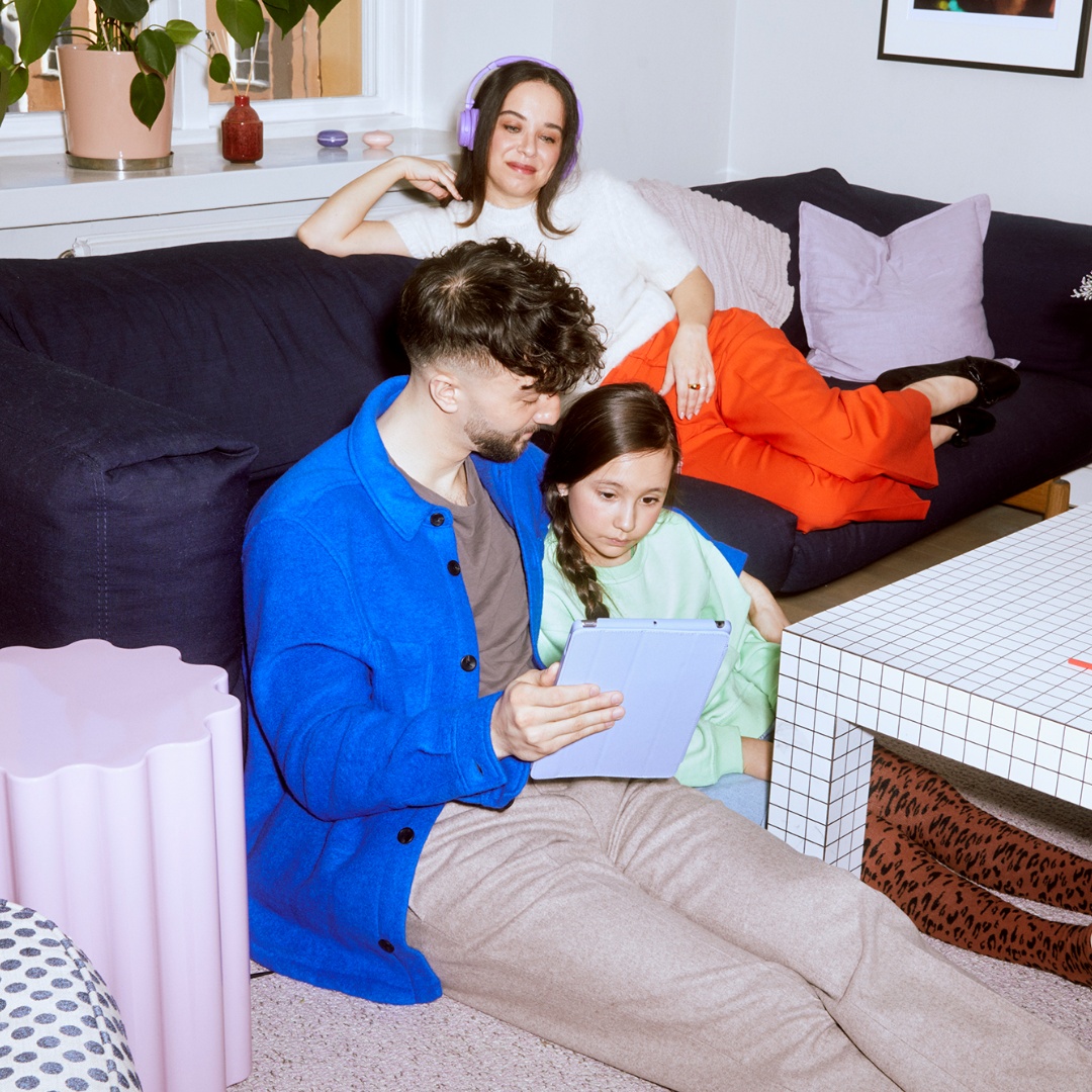 En pappa, mamma och deras flicka sitter på golvet och lyssnar på ljudbok.