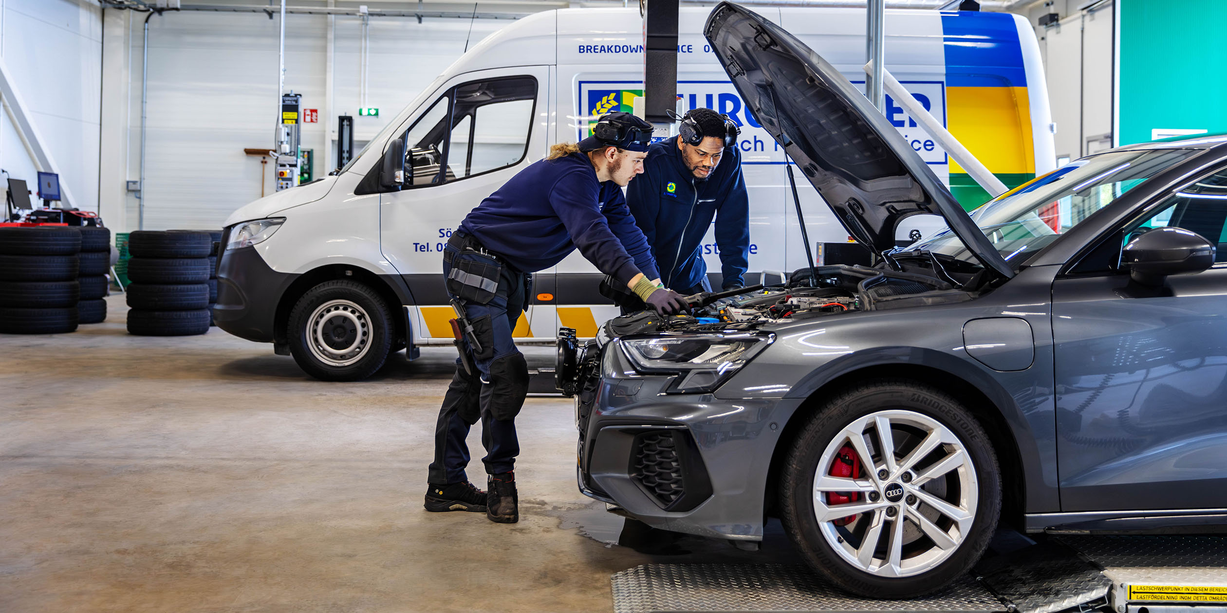 Två mekaniker tittar under motorhuven på en bil på en Euromaster verkstad.