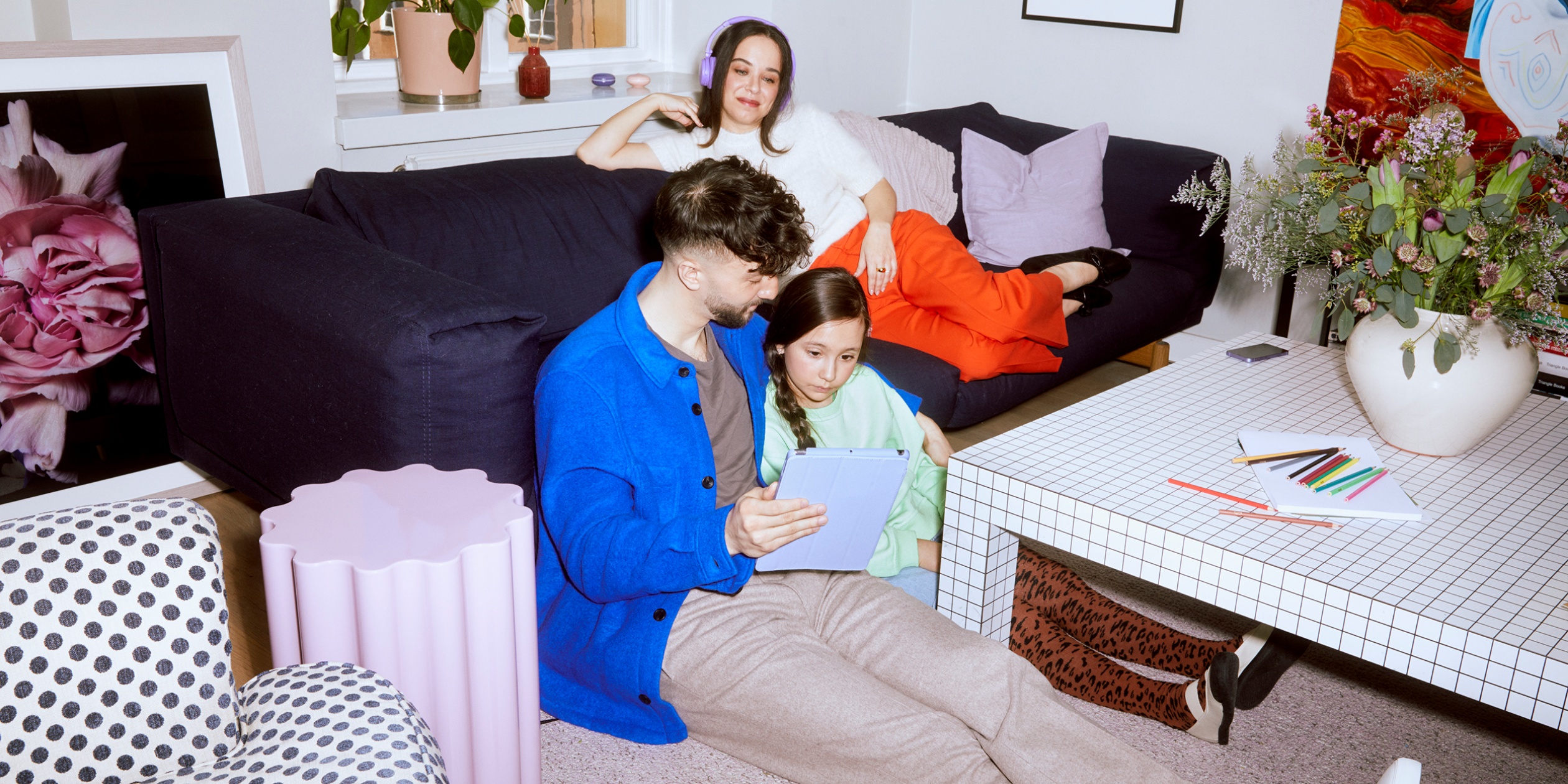 En pappa, mamma och deras flicka sitter på golvet och lyssnar på ljudbok.