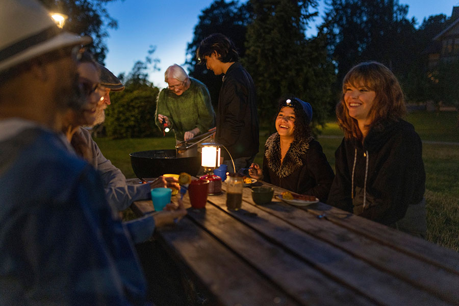 Flera personer runt ett bort utomhus på kvällen. Beredskapsveckan
