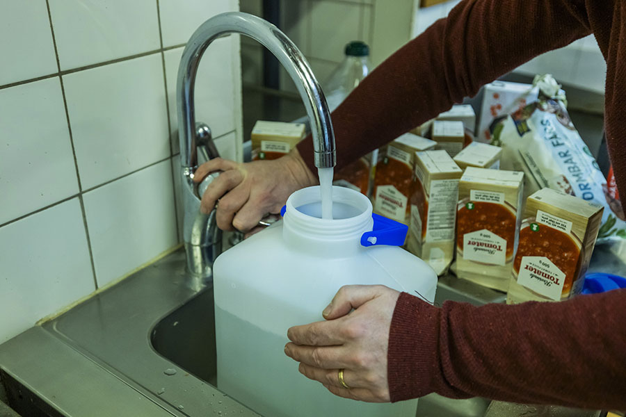 En vattendunk fylls på i en diskho och på den står det flera förpackningar krossade tomater.